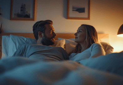 I bilden ser vi ett par i ett mysigt sovrum, som njuter av en lugn stund i sängen. Den dämpade belysningen från en hängande lampa skapar en varm och avkopplande atmosfär. Målningar på väggen och prydnadsföremål på byrån först