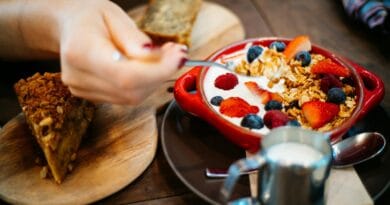 Close-up of a breakfast setting with granola, fresh berries, and a slice of cake.
