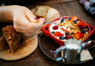 Close-up of a breakfast setting with granola, fresh berries, and a slice of cake.