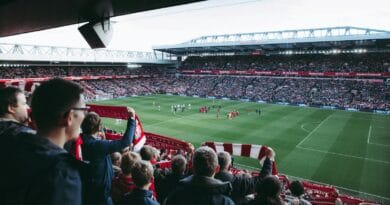 Fans cheer as players take the field at a vibrant football stadium, creating an electric atmosphere.