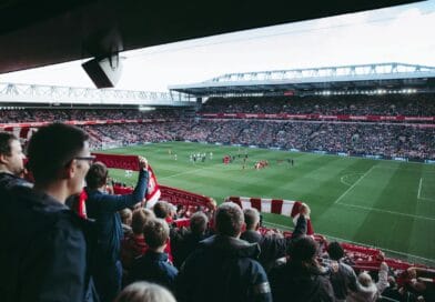 Fans cheer as players take the field at a vibrant football stadium, creating an electric atmosphere.