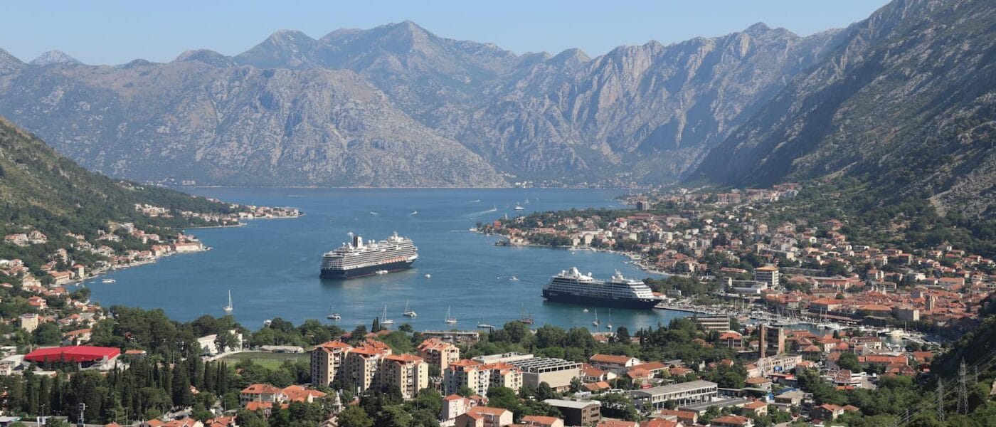 Scenic panorama of Kotor Bay with cruise ships and historic town surrounded by mountains.