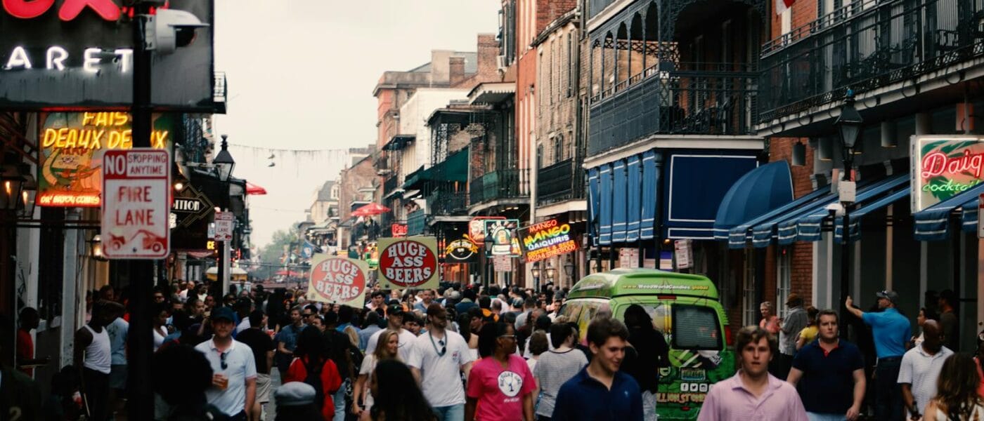 Bustling street scene in the New Orleans French Quarter filled with tourists and local shops.