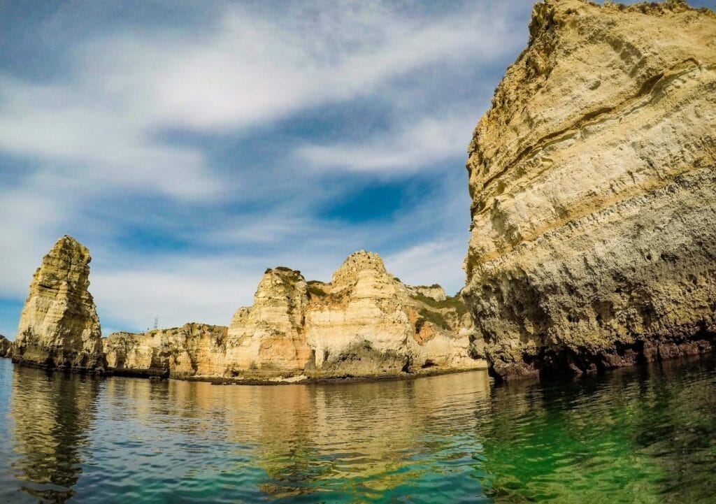 Dramatic limestone cliffs of Lagos, Portugal against a vibrant sky and serene sea.