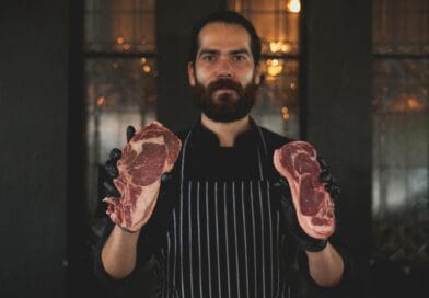 Bearded chef showcasing raw steaks, perfect for culinary arts and cooking themes.