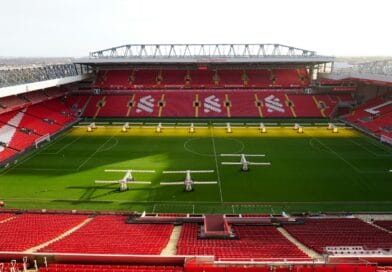 a soccer stadium with a green field and red seats