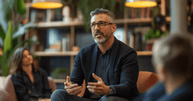 Personen i bilden talar engagerat under en workshop i ett modernt kontor, omgiven av gröna växter och uppmärksamma deltagare. Fokus på kommunikation och ledarskap i en kreativ miljö. Midcent. Kategori: Samhälle.