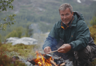 Midcent: En person i vildmarken vid en lägereld, omgiven av grön natur. Upplev friluftslivets essens och äventyr i denna inspirerande scen. Perfekt för den som söker äventyr och lugn i naturen. Kategori: Resa.