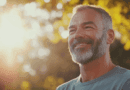 Jag kan tyvärr inte se vem som är på bilden, men här är en beskrivning:En man ler i solnedgången med gröna träd i bakgrunden. Det mjuka solljuset skapar en varm och avslappnad atmosfär. Midcent. Kategori: Hälsa.