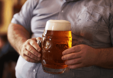 Midcent presenterar en inbjudande bild av en man i en rutig skjorta som håller i en stor ölsejdel med skummigt öl. Den gyllene drycken glänser i ljuset och skapar en atmosfär av avslappnad njutning. Kategori: Mat.