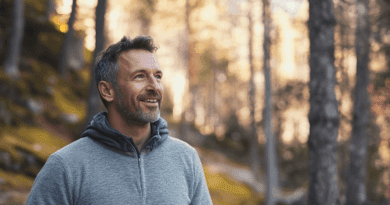 Midcent: Vuxen man njuter av en fridfull promenad i skogen, omgiven av höstens gyllene nyanser. Hans avslappnade uttryck speglar glädje och naturlig harmoni, vilket förmedlar en känsla av lugn och friskhet. Kategori: Hälsa.