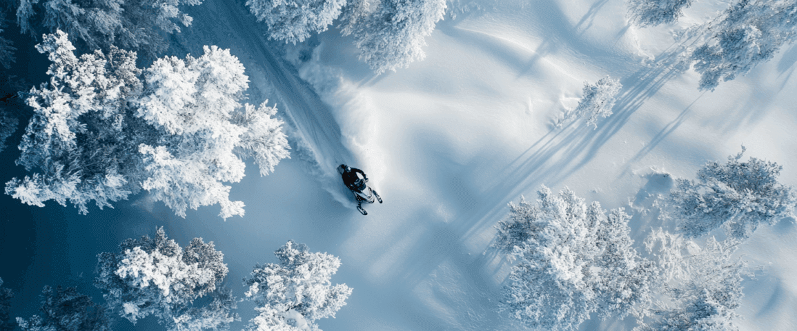 Midcent: En snöskoter kör genom ett vintrigt landskap av snötäckta träd, vilket skapar en känsla av äventyr och frihet i den friska vinterluften. Perfekt för dem som söker spänning i kalla klimat. Kategori: Sport.