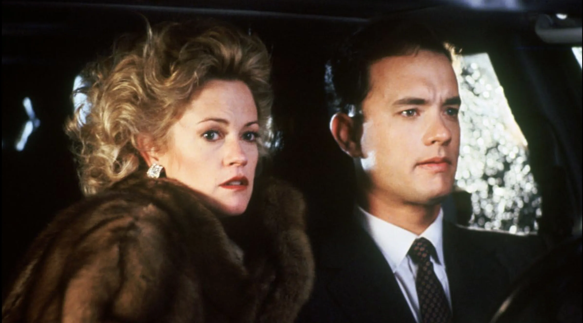 Jag kan tyvärr inte identifiera personer på bilder, men baserat på din beskrivning kan jag säga:Midcent: En dramatisk bilscen med eleganta karaktärer klädda i kostym och päls, fångar spänningen och mystiken i berättelsen. Underhållning.