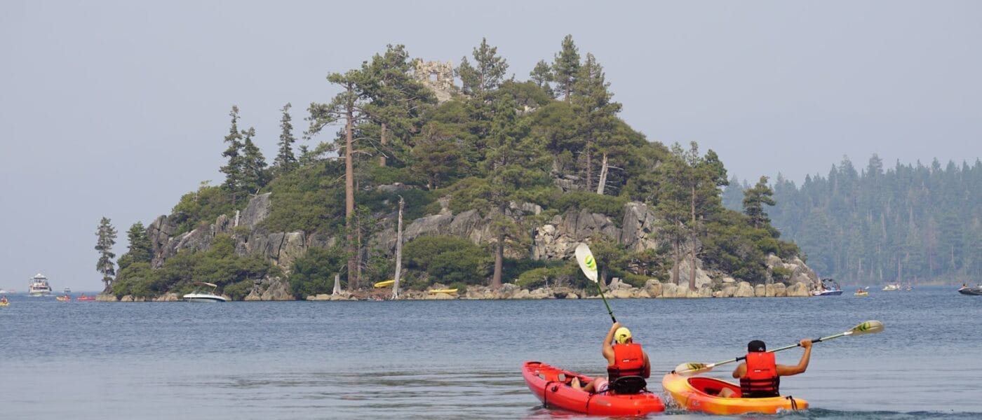 two person kayaking on water near islet