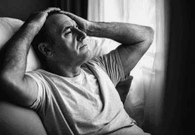 En eftertänksam man i svartvitt, sittandes inomhus och blickande ut genom ett fönster. Relaterad till stress och reflektion. Midcent. Hälsa.