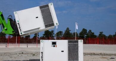 Midcent: Bilden visar en mobil energi- och kraftlösning från Northvolt. Perfekt för hållbar energiutveckling, den dokumenterar installation eller flytt av batterisystemet i en industriell miljö med klarblå himmel. Kategori: Teknik.