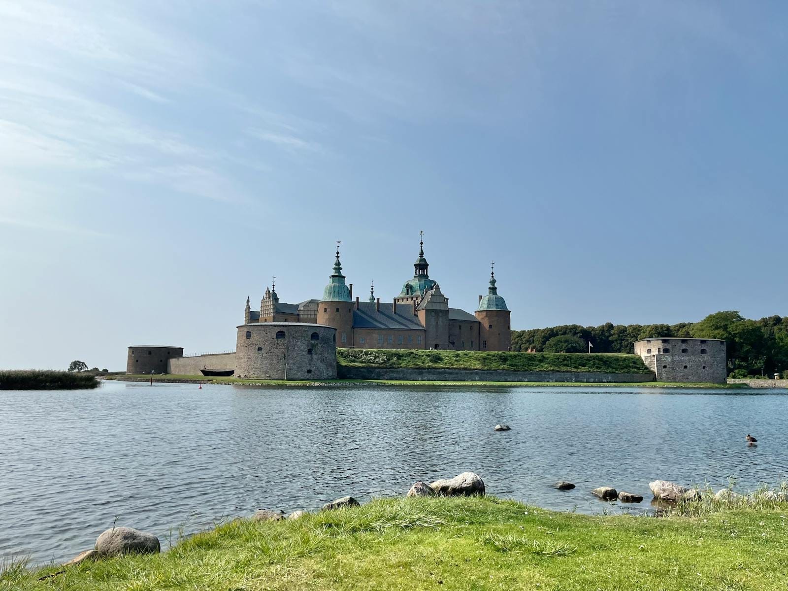 Stunning view of Kalmar Castle with its reflection in the water on a clear summer day.