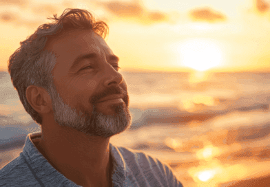 Midcent: En man står leende vid en solnedgång vid havet, njuter av den lugnande stunden och den vackra utsikten. Kategorin är Resa.