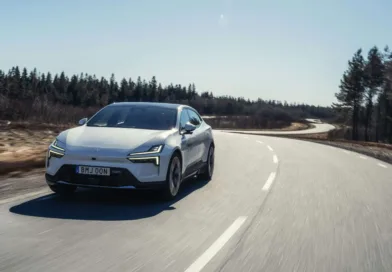 På bilden syns en elbil i rörelse längs en slingrig landsväg med skog i bakgrunden. Bilen har en modern och stilren design, vilket symboliserar framtidens bilteknik. Midcent - Teknik.