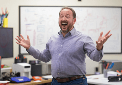 Midcent: En entusiastisk man står i ett kontorsmiljö, omgiven av teknik och whiteboards. Hans utstrålning förmedlar glädje och inspiration, vilket betonar en engagerad och positiv arbetskultur. Kategori: Samhälle.