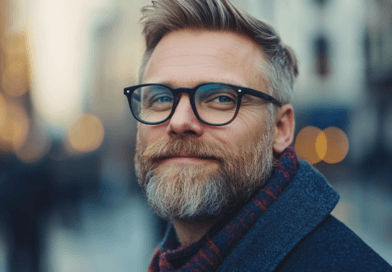 Jag vet inte vem personen på bilden är. Den föreställer en man med glasögon och skägg, klädd i en vinterscarf i en urban miljö med bokeh-effekt. Midcent, kategori: Samhälle.