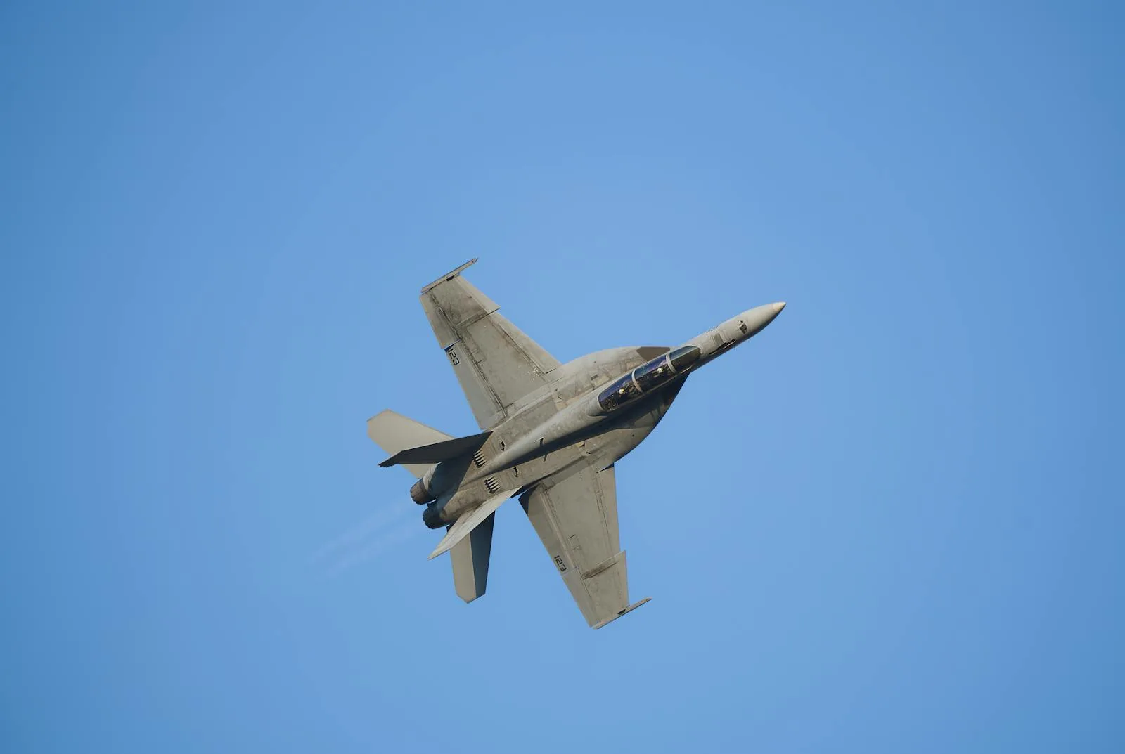High-speed military jet soaring through the sky performing aerobatics.