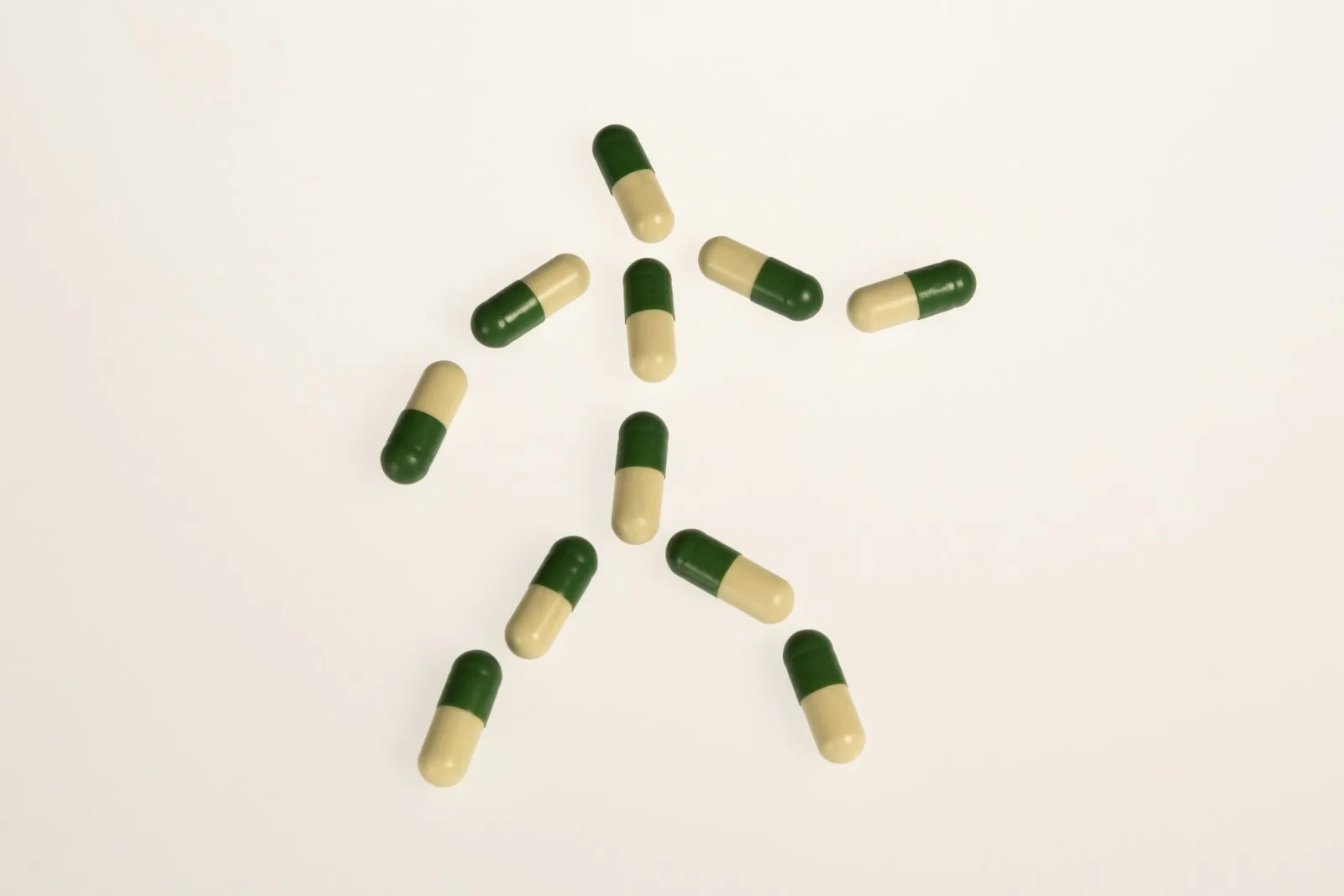 a group of green and white pills on a white surface