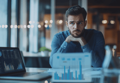 Midcent: En medelålders man framför en dator med datadiagram, visuellt stressad. Affärsmiljö med fokus på ekonomiska utmaningar och arbetsrelaterade beslut. Business casual-klädsel. Kategorin: Ekonomi.