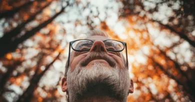 Midcent: En medelålders man njuter av naturens skönhet med varm höstbakgrund och bokeh-effekt i en skogslandskap. Bilden fångar lugn och reflektion, perfekt för artiklar om mindfulness och naturens påverkan på välbefinnande. Kategori: Hälsa.