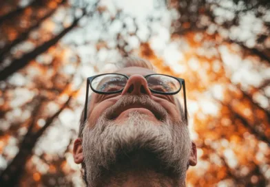 Midcent: En medelålders man njuter av naturens skönhet med varm höstbakgrund och bokeh-effekt i en skogslandskap. Bilden fångar lugn och reflektion, perfekt för artiklar om mindfulness och naturens påverkan på välbefinnande. Kategori: Hälsa.