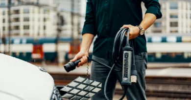 a man standing next to a white car with a power cord attached to it