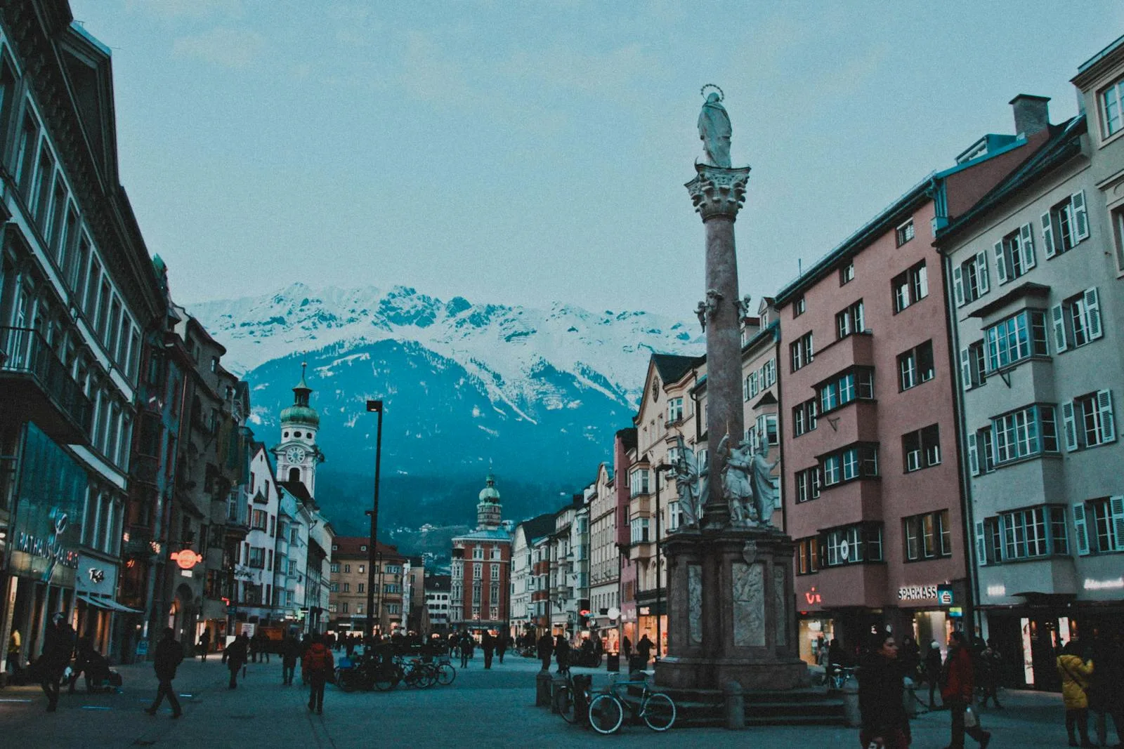 Bustling street in Innsbruck, Austria, with historical buildings and the Alps in the background.