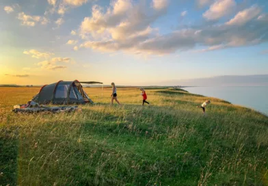 toddler walking on green grass with set-up tent during golden hour