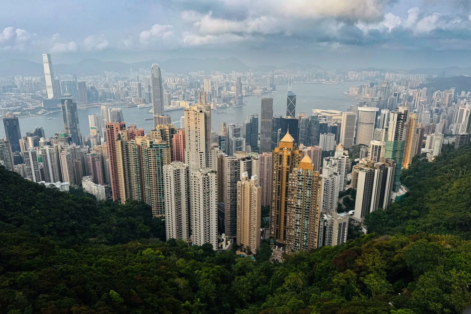 Hisnande flygbild av Hongkongs silhuett från Victoria Peak, som visar upp höga skyskrapor och frodig grönska.