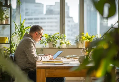 Midcent: En medelålders man arbetar vid en ljusfylld arbetsplats med mycket grönska och modern teknik, vilket skapar en