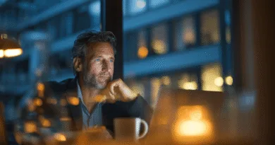 Midcent, en medelålders man fokuserar vid en laptop i ett stämningsfullt upplyst kontor. Bilden fångar kreativitet och reflektion under sena arbetstimmar. Perfekt för artiklar om arbetsliv, innovation eller teknik. Kategori: Teknik.