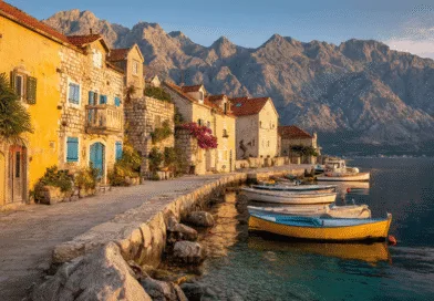 Midcent: En pittoresk kustby med solbelysta stenhus, färgglada båtar och majestätiska berg i bakgrunden. Den lugna vattenytan speglar byns charm och kultur, perfekt för den som söker en idyllisk semesterupplevelse. Resa.