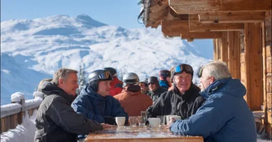 Midcent: En grupp medelålders män njuter av en solig vinterdag på en skidort, samlade kring ett bord med varma drycker.