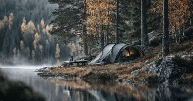 Midcent: En fridfull campingplats vid en spegelblank sjö omgiven av höstens färgskiftningar i skogen. Perfekt tillflykt för naturälskare och äventyrslystna. Känsla av ro och stillhet i det fria. Resa.