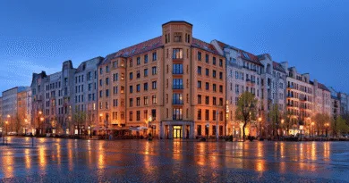 Midcent: En stadsbild i skymning där ljusen reflekteras på den blöta gatan, omgivna av klassisk europeisk arkitektur som skapar en stämningsfull atmosfär. Perfekt för resenärer som söker urban charm och nattliv. Kategori: Resa.