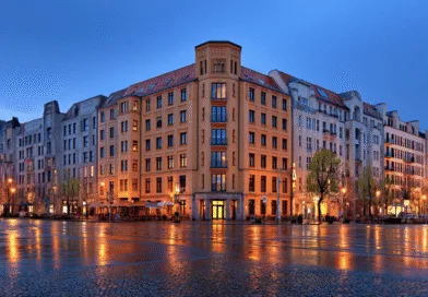 Midcent: En stadsbild i skymning där ljusen reflekteras på den blöta gatan, omgivna av klassisk europeisk arkitektur som skapar en stämningsfull atmosfär. Perfekt för resenärer som söker urban charm och nattliv. Kategori: Resa.