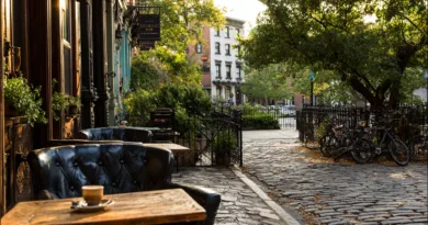 Upplev den charmiga atmosfären i en stadsmiljö med Midcent, där solens strålar belyser en mysig caféterass. Njut av en kopp kaffe i en lugn gata med grönska och cyklar i bakgrunden. Kategori: Samhälle.