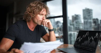 Builder.ai – När Silicon Valley-drömmar möter svensk skepsis Midcent ekonomi: En medelålders man analyserar aktiemarknaden vid en laptop. Han granskar pappersdokument och följer noggrant finansdiagram på skärmen. Bakgrunden visar en stads siluett genom fönstret, vilket förstärker fokus på ekonomi och investeringar.
