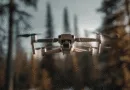 Midcent presenterar en avancerad drönare i luften, omgiven av skogslandskap. Den senaste tekniken inom drönarflygning visas upp, perfekt för övervakning och naturfotografering. Optimera ditt flygfotoäventyr med banbrytande funktioner. Kategori: Teknik.