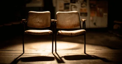 Midcent: Två slitna stolar i en dunkel miljö skapar en nostalgisk atmosfär med skuggor och ljus som spelar över trägolvet. Detta konstnärliga motiv väcker tankar och känslor. Underhållning.