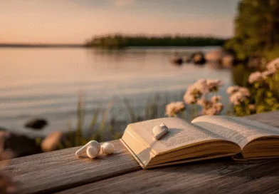 Midcent: Sommaravkoppling vid en sjö med en öppen bok och trådlösa hörlurar på en träbänk. Perfekt för solnedgångsläsning och naturens lugn. Vacker miljö med blommor och vatten i bakgrunden. Kategori: Resa.