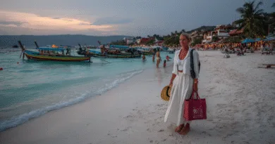 Midcent: En kvinna promenerar längs en solnedgångsbelyst strand med traditionella båtar i bakgrunden. Perfekt för avkoppling och semesterupplevelser. Kategorin är Resa.