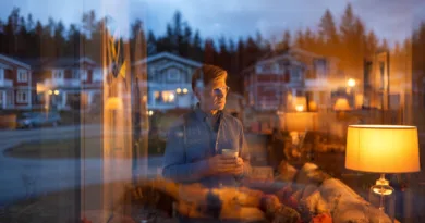 Midcent erbjuder en lugn och reflekterande atmosfär, perfekt för tankar och avkoppling. En medelålders man står vid fönstret med en kopp i handen, omgiven av varm belysning.Kategori: Samhälle.