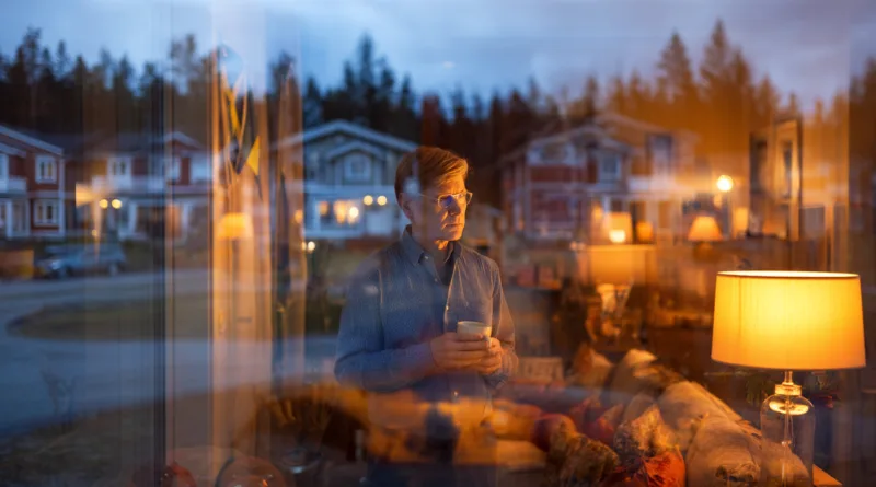 Midcent erbjuder en lugn och reflekterande atmosfär, perfekt för tankar och avkoppling. En medelålders man står vid fönstret med en kopp i handen, omgiven av varm belysning.Kategori: Samhälle.