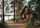 Midcent: En idyllisk svensk sommarstuga inbäddad i tät skog vid en sjö, med en cykel och vedhög på verandan. Perfekt för naturälskare och en avkopplande tillflykt från vardagens stress. Kategori: Resa.